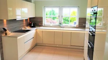 kitchen using glass effect acrylic door fronts and a light wood contrast